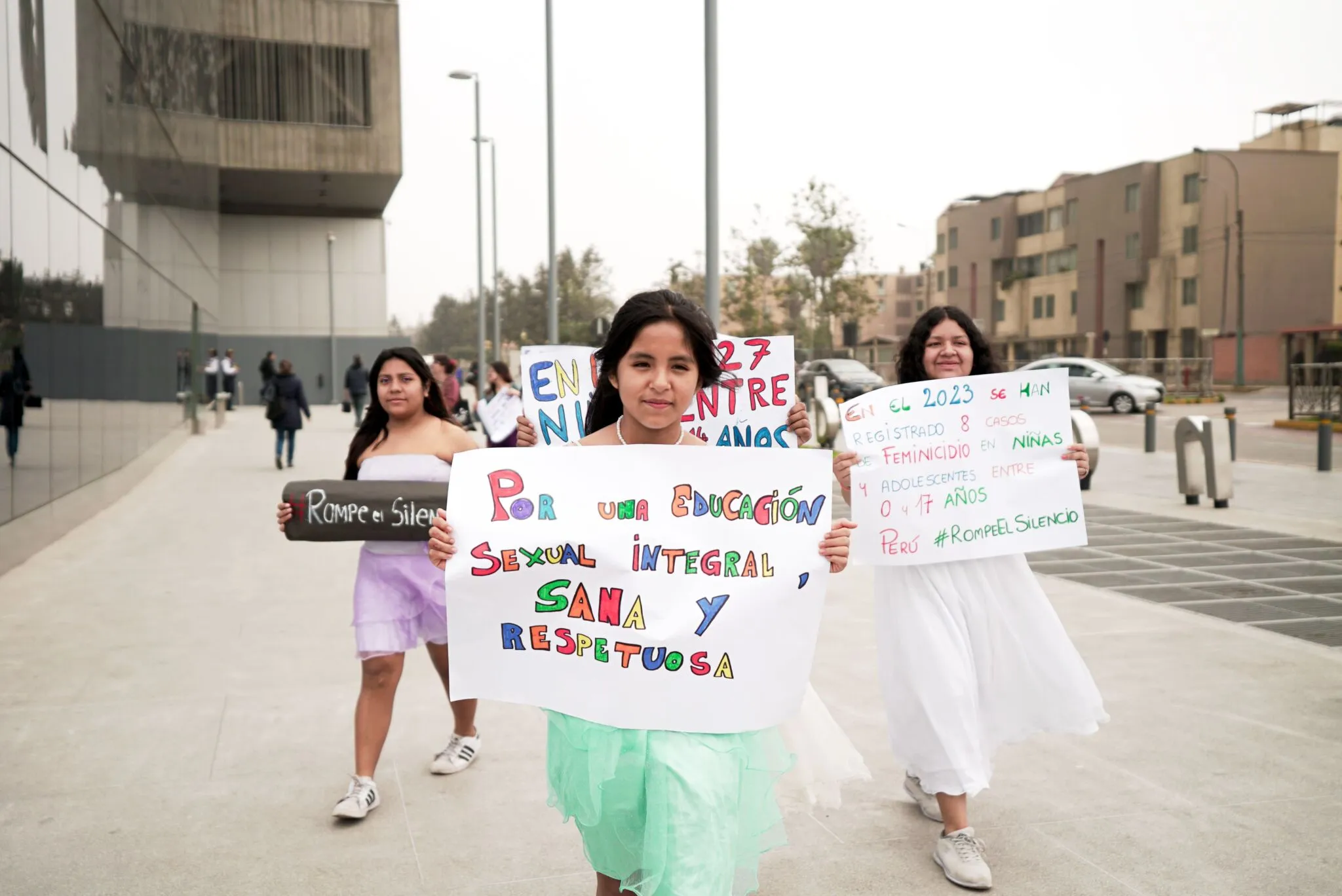 Tres adolescentes marchan con carteles hechos a mano por sus derechos.